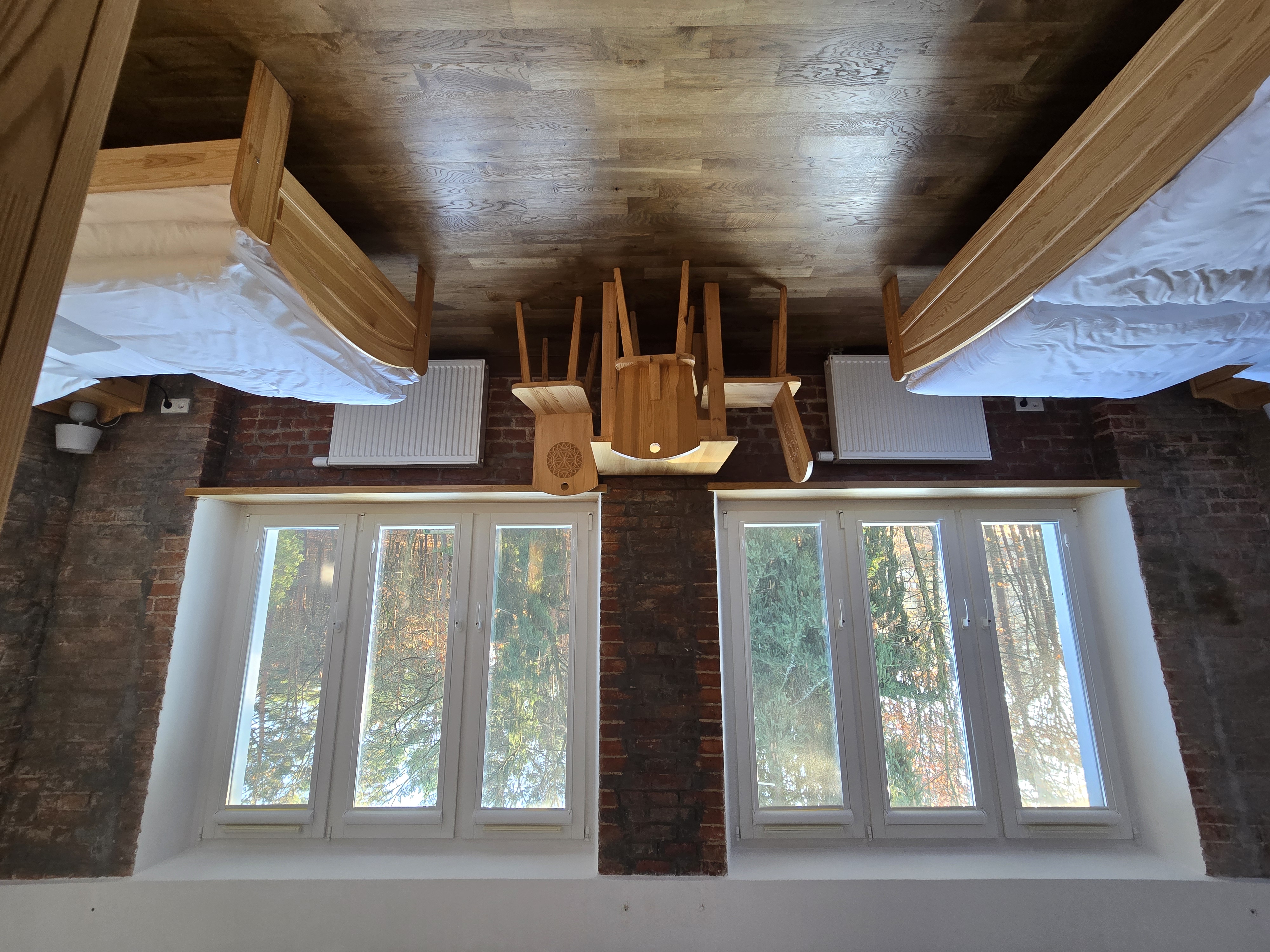 Przestronny pokój z dwoma wygodnymi łóżkami oraz dużymi oknami z których widok rozpościera się na pobliskie lasy